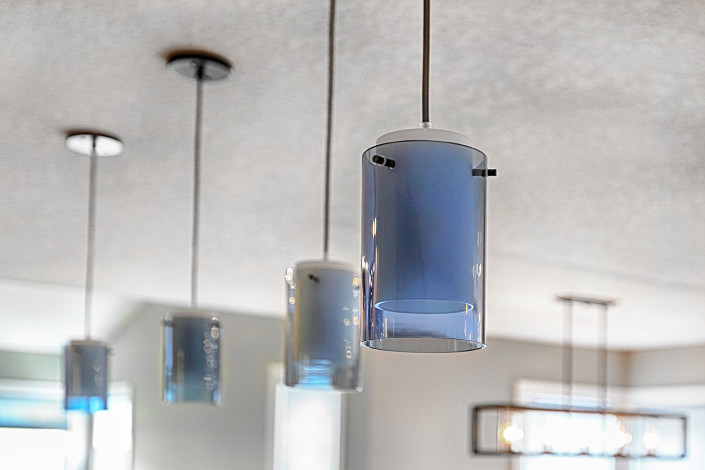Clear blue glass pendant lights over the island. By House of J Interior Design. Edmonton, Alberta.