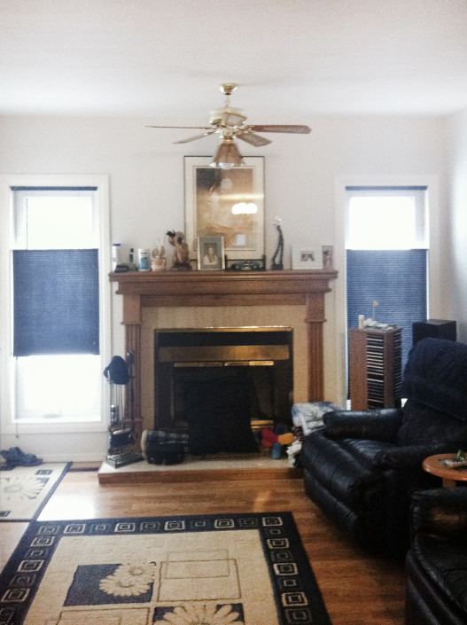 Before photo of family room. Dated fireplace, old ceiling fan.